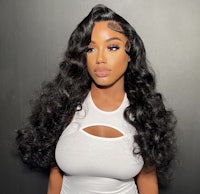 a black woman wearing a white top with long wavy hair