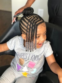 a little girl getting her hair braided in a salon