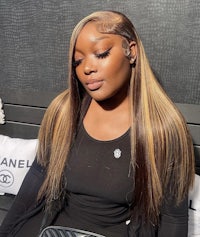 a black woman with long hair sitting on a bench